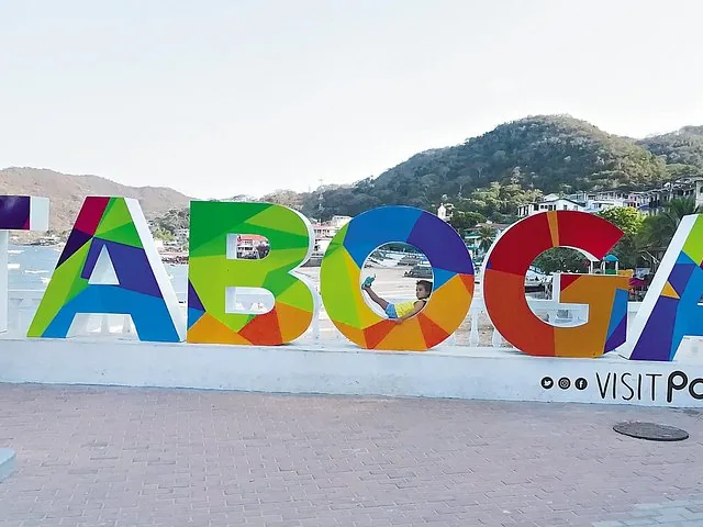 Child playing inside the colorful Taboga sign near the island's beach