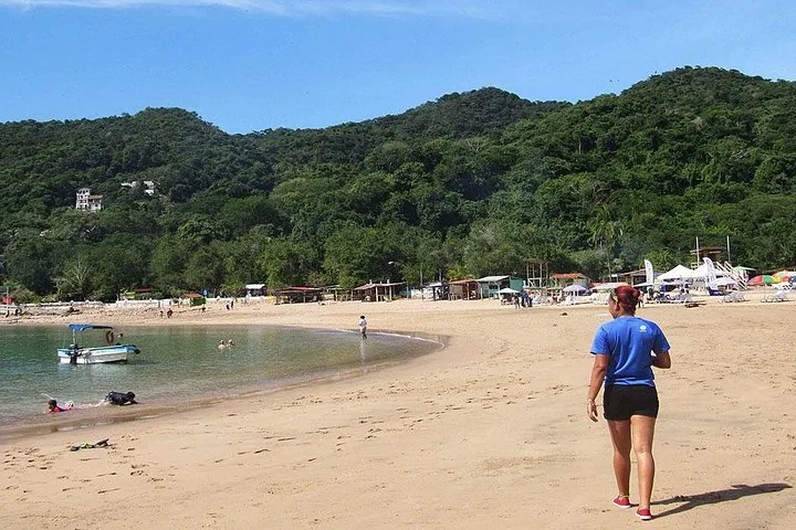 People walking on the sandy beach of Taboga Island near green hills