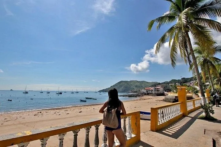 Woman looks out over the beach and boats from a yellow balcony
