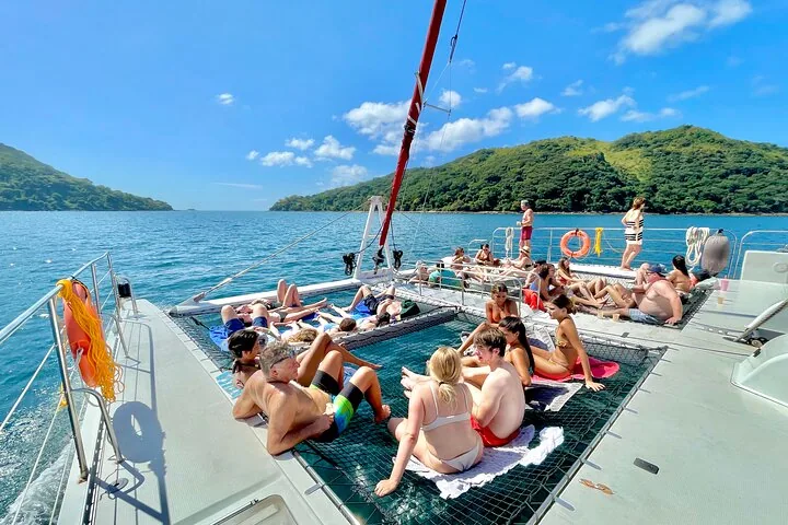 Group of people sunbathing and relaxing on the nets of a large catamaran