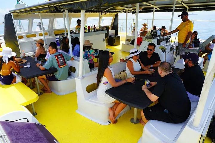 Passengers sitting at tables inside the covered area of a tour boat